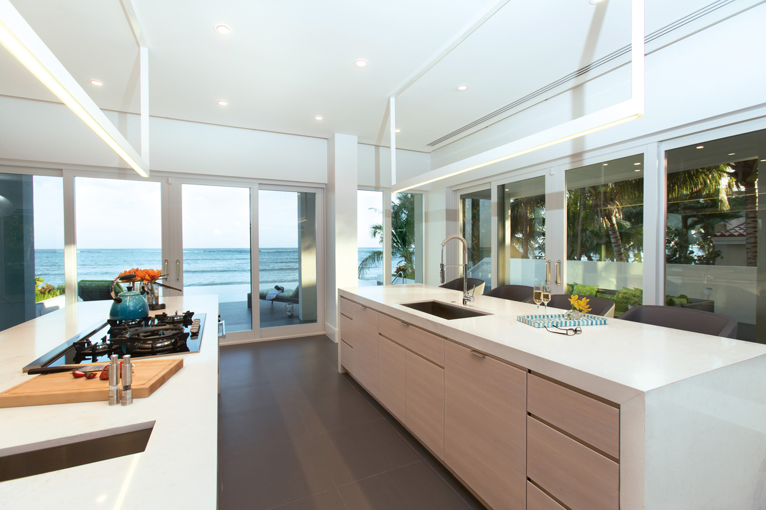 Custom millwork in mixed materials of high gloss white and satin white, with hidden finger drawer pulls, create a seamless look in the kitchen.